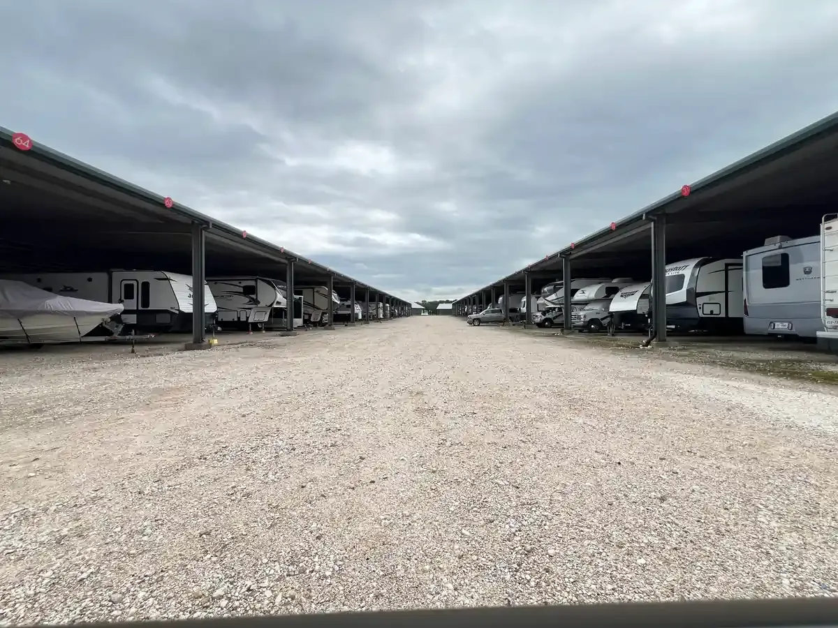 RVs under a covered awning on gravel driveway